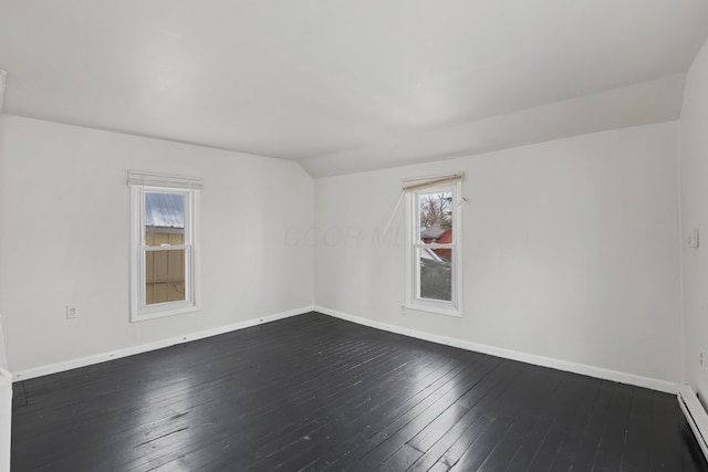 spare room with dark wood-style flooring, vaulted ceiling, and baseboards