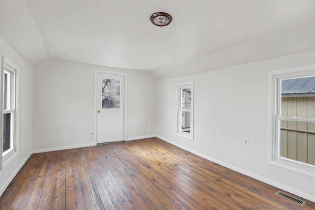 spare room featuring lofted ceiling, hardwood / wood-style floors, visible vents, and baseboards