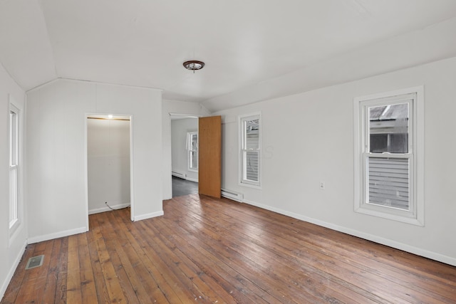 unfurnished bedroom with lofted ceiling, wood-type flooring, visible vents, and a baseboard heating unit