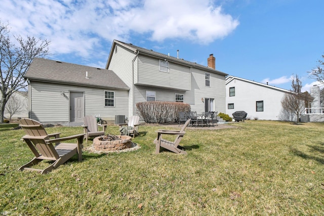 back of property with a shingled roof, a patio, a yard, and an outdoor fire pit