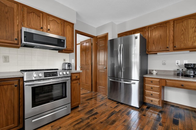 kitchen with dark wood-type flooring, brown cabinetry, appliances with stainless steel finishes, and light countertops