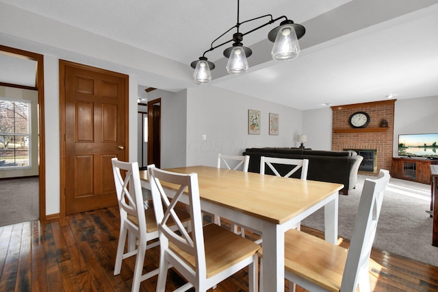 dining area featuring a brick fireplace and dark wood-style flooring