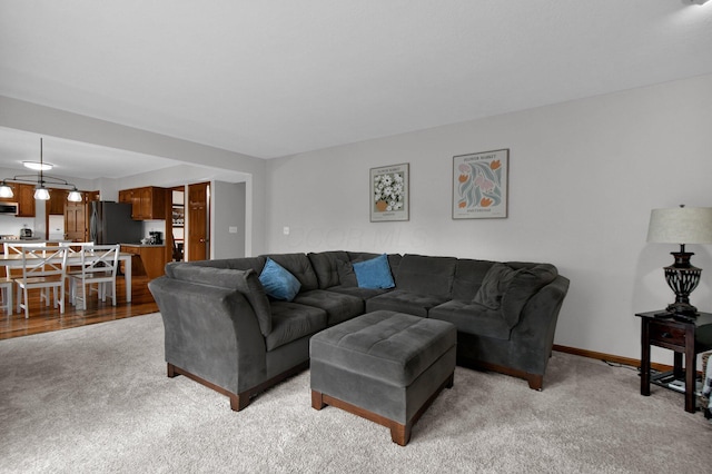 living area with light carpet and baseboards