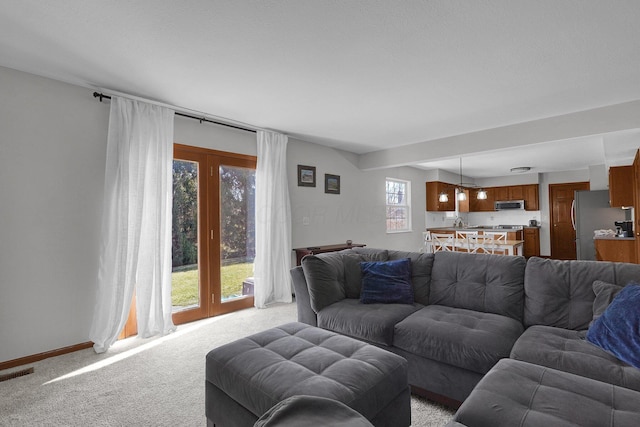 living room featuring visible vents, light carpet, and baseboards