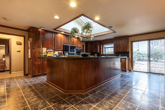 kitchen featuring a skylight, dark countertops, a center island, crown molding, and recessed lighting