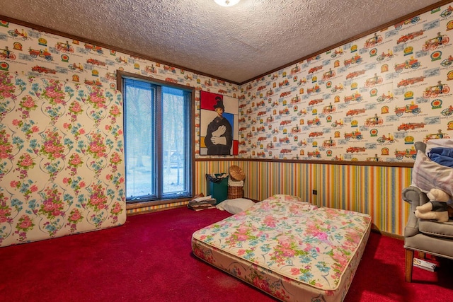 carpeted bedroom with wainscoting, multiple windows, a textured ceiling, and wallpapered walls