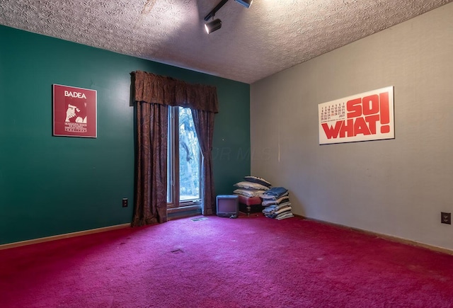 unfurnished room with carpet, a textured ceiling, and baseboards