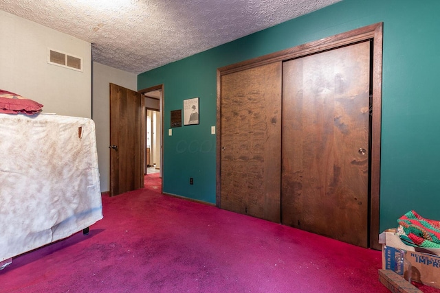 carpeted bedroom with a closet, visible vents, and a textured ceiling