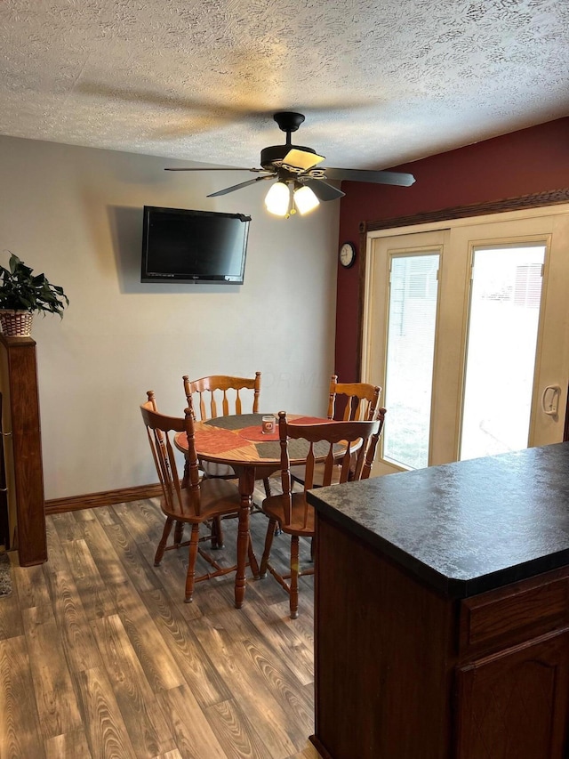 dining space featuring a textured ceiling, dark wood-type flooring, a ceiling fan, and baseboards