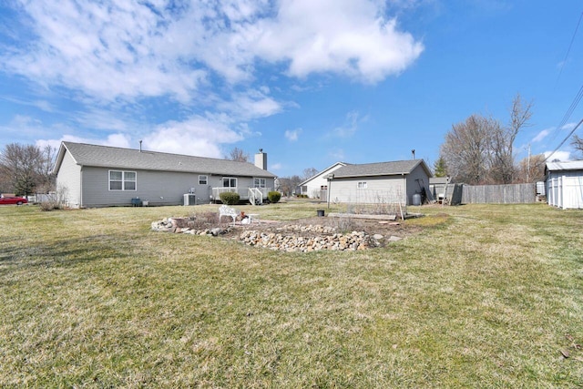 rear view of property with cooling unit, an outbuilding, a lawn, and fence