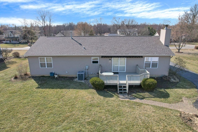 rear view of house featuring central air condition unit, a wooden deck, roof with shingles, a lawn, and a chimney