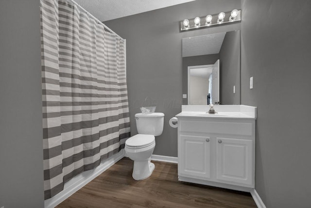 bathroom featuring vanity, wood finished floors, baseboards, a textured ceiling, and toilet