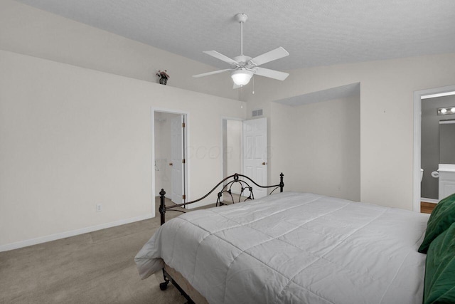 carpeted bedroom featuring visible vents, ensuite bathroom, a textured ceiling, baseboards, and vaulted ceiling