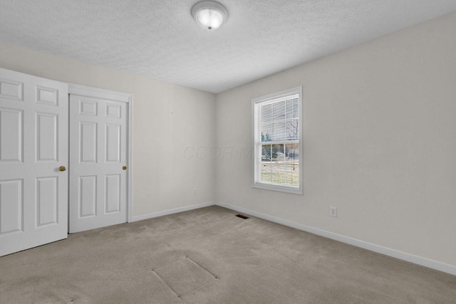 unfurnished bedroom with carpet, baseboards, and a textured ceiling