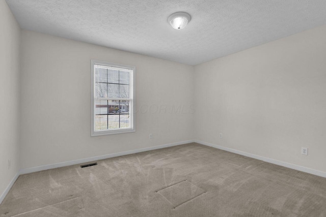 spare room featuring visible vents, baseboards, carpet, and a textured ceiling