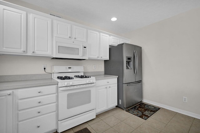 kitchen featuring baseboards, light countertops, light tile patterned floors, white cabinets, and white appliances