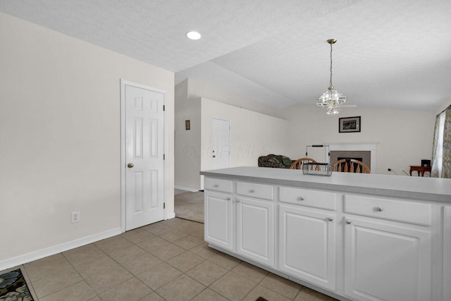 kitchen featuring vaulted ceiling, light countertops, pendant lighting, white cabinetry, and a notable chandelier