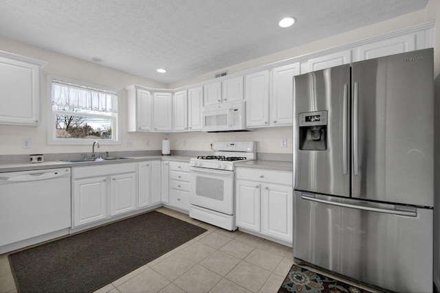 kitchen with a sink, white appliances, light tile patterned flooring, white cabinets, and light countertops