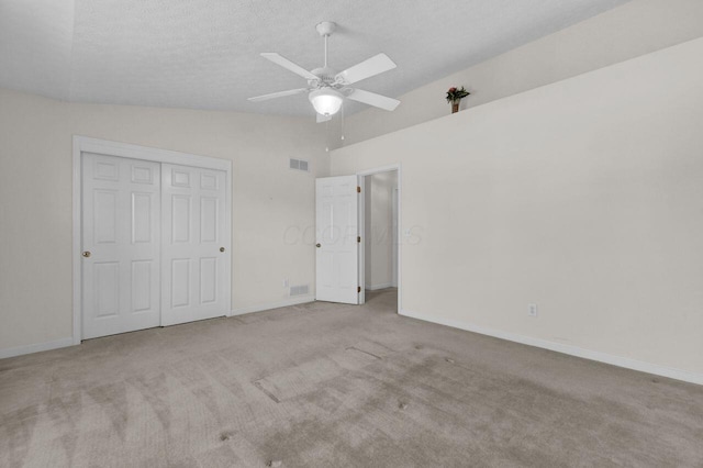 unfurnished bedroom featuring visible vents, carpet, lofted ceiling, a closet, and a textured ceiling