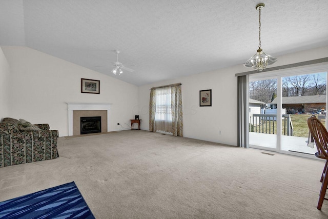 carpeted living area with visible vents, a fireplace with flush hearth, vaulted ceiling, a textured ceiling, and ceiling fan with notable chandelier