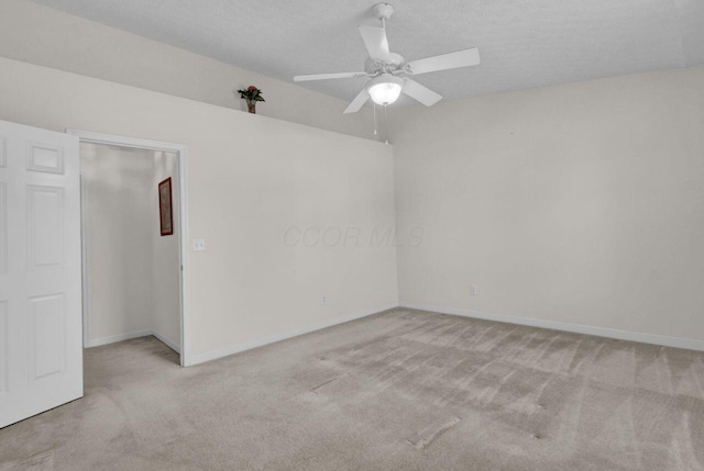 carpeted spare room with baseboards, a textured ceiling, and a ceiling fan