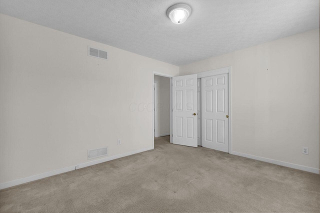 unfurnished bedroom with visible vents, carpet flooring, a textured ceiling, and baseboards