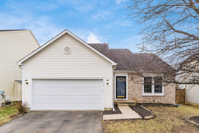 view of front of property featuring brick siding, driveway, an attached garage, and fence