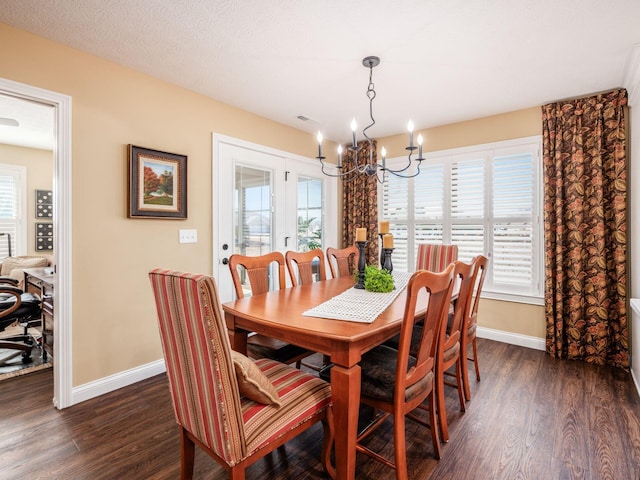 dining area featuring a chandelier, visible vents, dark wood-type flooring, and baseboards