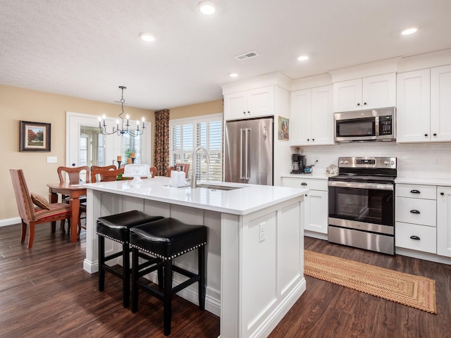 kitchen featuring visible vents, light countertops, appliances with stainless steel finishes, a kitchen breakfast bar, and a sink