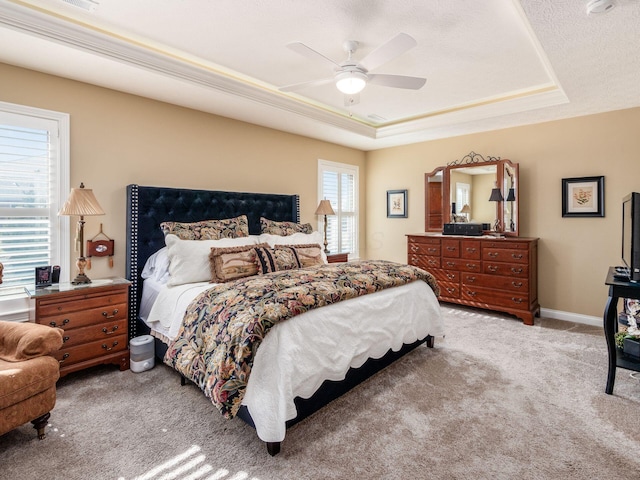 bedroom featuring ceiling fan, baseboards, a tray ceiling, and carpet floors