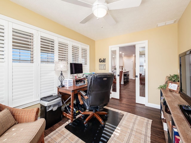 office space featuring a ceiling fan, wood finished floors, visible vents, baseboards, and a textured ceiling