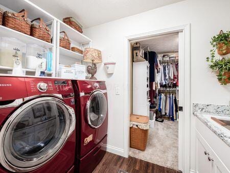 clothes washing area featuring dark wood finished floors, laundry area, and washing machine and clothes dryer