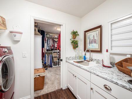 laundry area with dark wood-style floors, cabinet space, washer / clothes dryer, and a sink