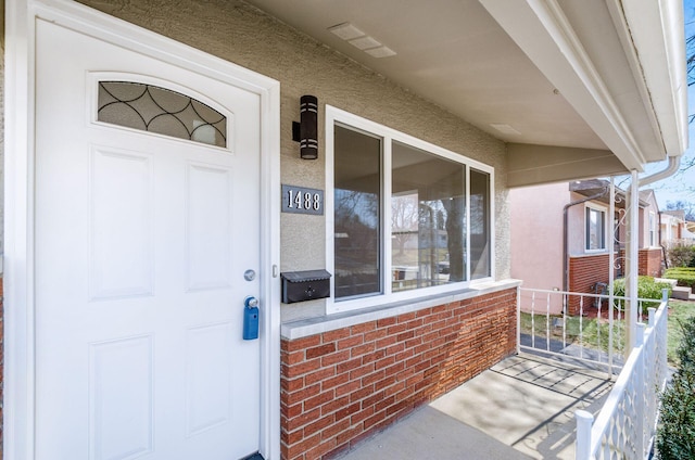 view of exterior entry featuring visible vents and brick siding