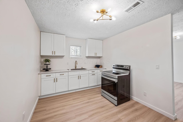 kitchen with light wood finished floors, visible vents, electric stove, white cabinetry, and a sink