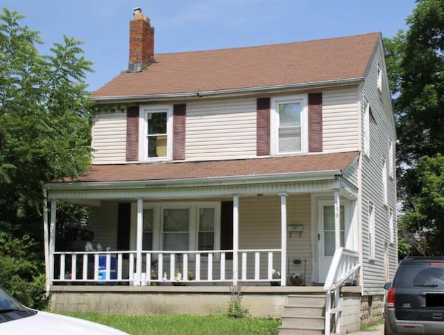 view of front of property featuring covered porch, roof with shingles, and a chimney