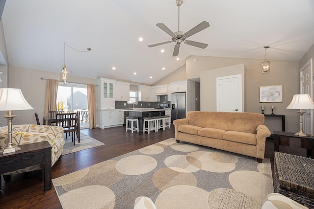 living area with dark wood finished floors, recessed lighting, ceiling fan with notable chandelier, and high vaulted ceiling