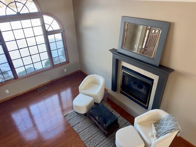 sitting room with baseboards, visible vents, wood finished floors, and a glass covered fireplace