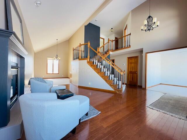 living area featuring baseboards, stairway, a notable chandelier, and wood finished floors