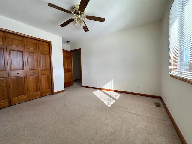 unfurnished bedroom with light colored carpet, visible vents, ceiling fan, and baseboards