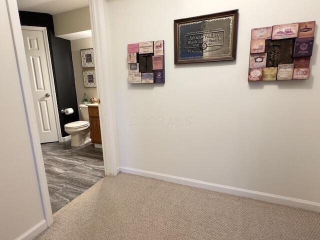 hallway featuring carpet flooring and baseboards