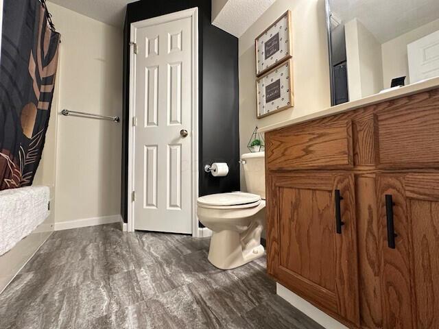 bathroom with curtained shower, baseboards, and toilet