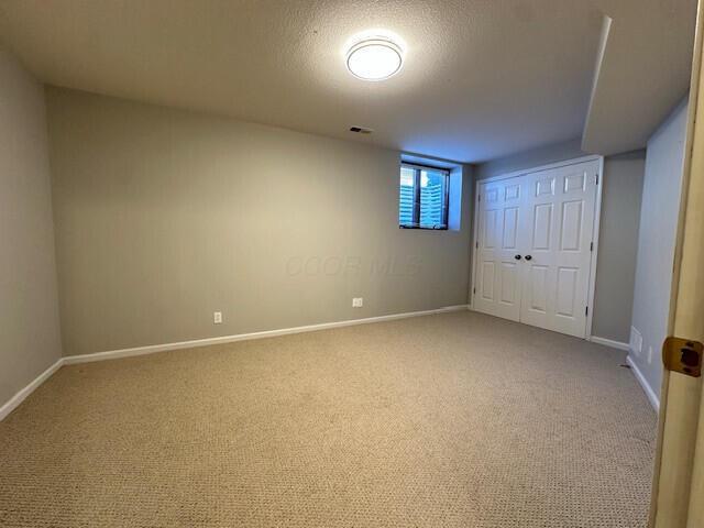 interior space with light carpet, a textured ceiling, visible vents, and baseboards