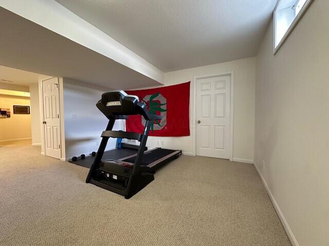 workout room featuring carpet and baseboards