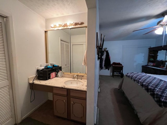 bathroom with a closet, a textured ceiling, ceiling fan, and vanity