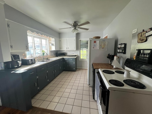 kitchen with white electric range oven, light tile patterned flooring, a sink, light countertops, and stainless steel microwave