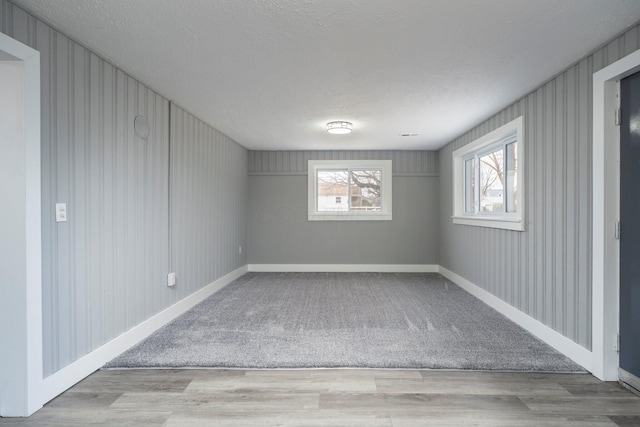 unfurnished room with a textured ceiling, wood finished floors, and baseboards