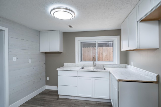 kitchen featuring dark wood finished floors, visible vents, a sink, and white cabinetry