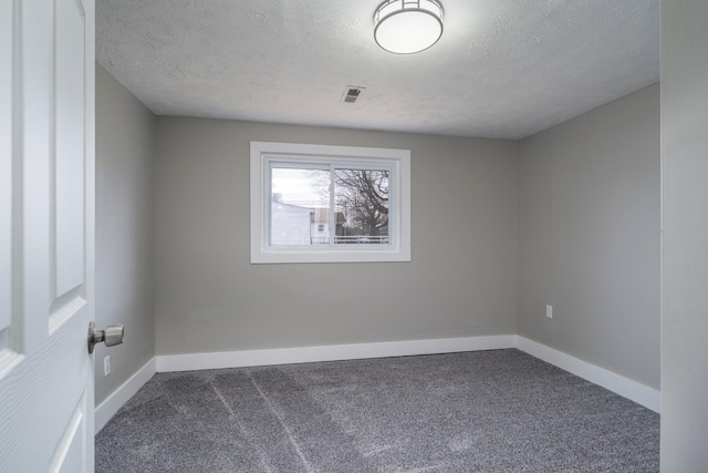 empty room with dark colored carpet, visible vents, a textured ceiling, and baseboards