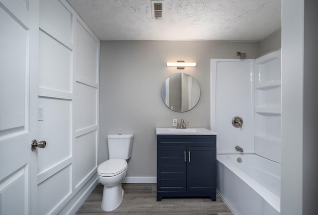 bathroom featuring toilet, tub / shower combination, a textured ceiling, vanity, and wood finished floors